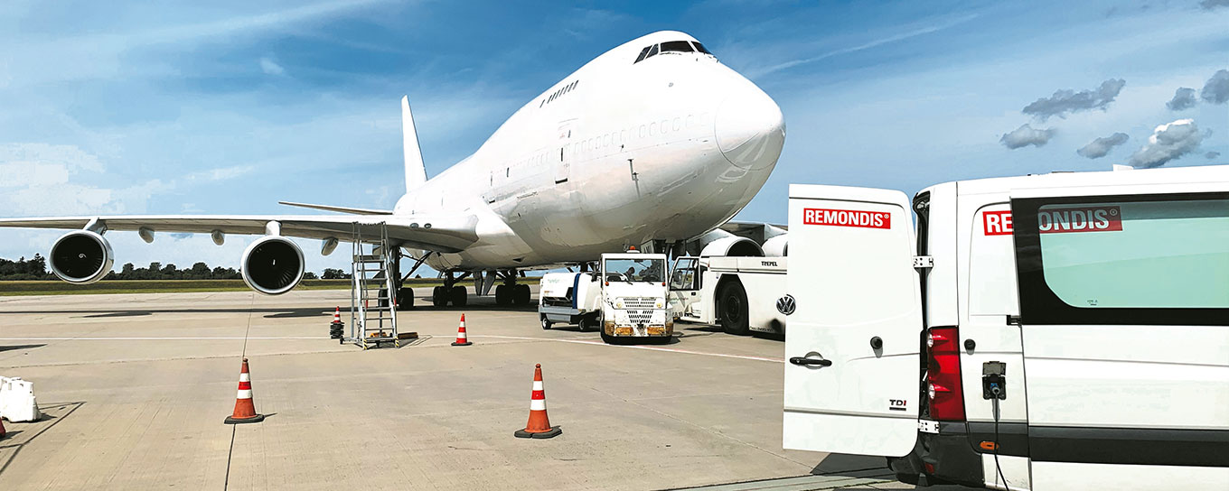 REMONDIS-Fahrzeug vor einem Frachtflugzeug am Flughafen